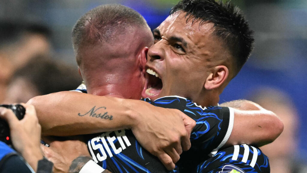 Two soccer players celebrate a goal with a tight hug on the field, faces lit with joy.