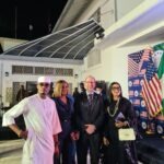 U.S. Mission Celebrates 250 Years Of American Independence In Lagos Group of formally dressed people posing for a photo at an event with US flags and a 'Freedom 250' backdrop at night