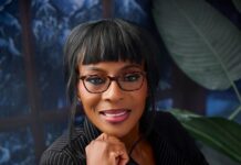 2027: Bolaji Odusina Emerges NDC Governship Candidate In Ogun Portrait of a smiling woman with short black hair and glasses, resting her chin on her hand in a professional setting.