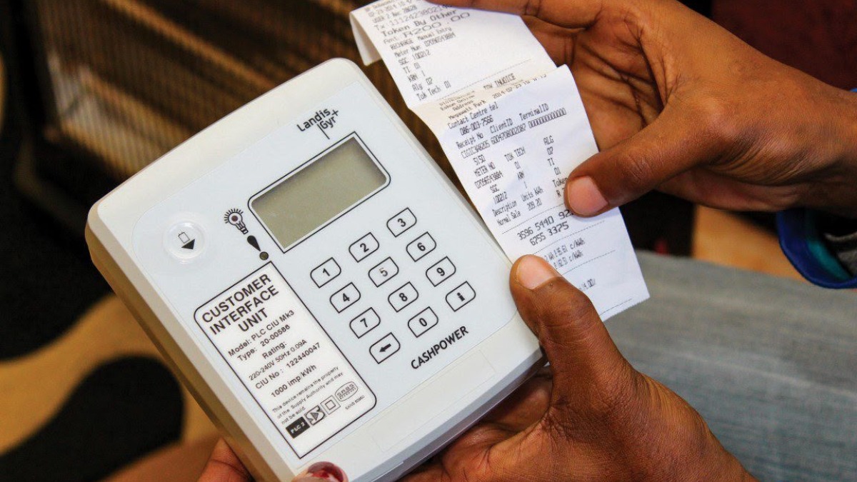 A handheld cash register-like device labeled'Customer Interface Unit' with a numeric keypad and a printed receipt being held by hands nearby.