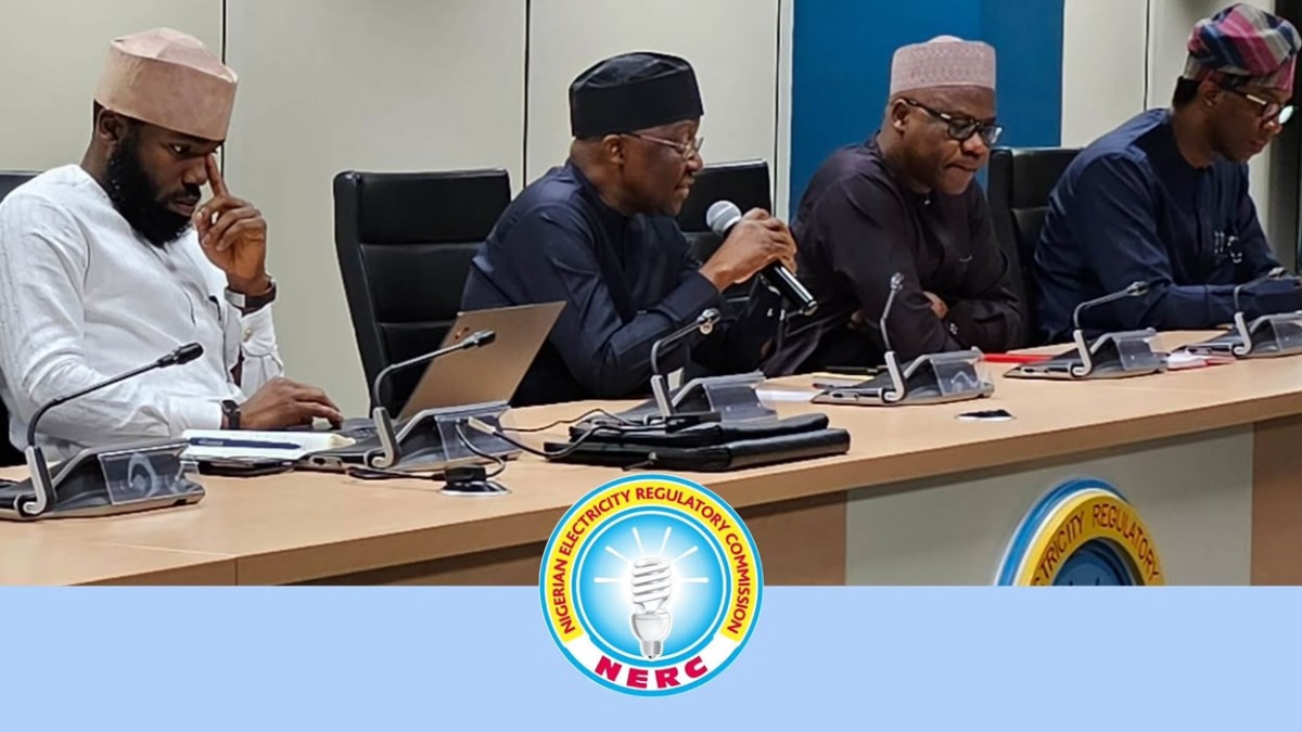 A panel of four men in traditional attire seated at a conference table with microphones and laptops, NERC logo in front.