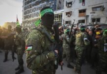 Hamas Ends 19-Year Rule of Gaza Masked soldier in camouflage with a green headband and rifle in a crowded urban street.