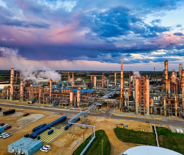 An active petroleum refinery processing facility. Source: Tom Fisk/Pex Industrial refinery with tall process towers, piping, and steam plumes under a blue sky.