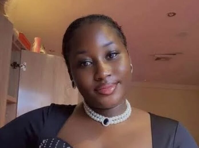 Deceased nurse- Mary Habila Portrait of a young woman indoors wearing a pearl choker and black dress, with a gentle smile.