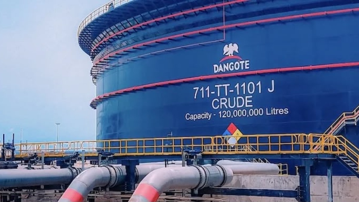 Large blue Dangote crude oil tank with capacity标 120,000,000 litres and yellow safety railing in foreground pipes in front