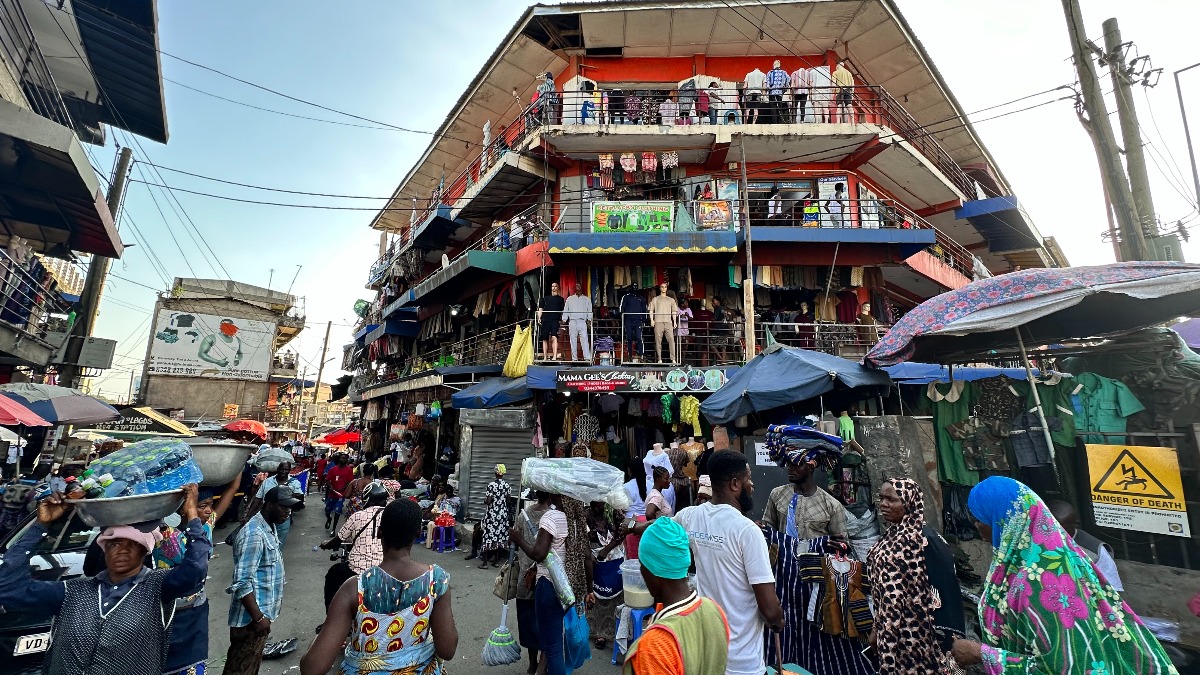 Passers-by, customers and traders visit the Makola market in the center of Ghana's capital. The market is considered one of the largest urban markets in Africa. [Photo Credit: Christina Peters//picture alliance via Getty Images]