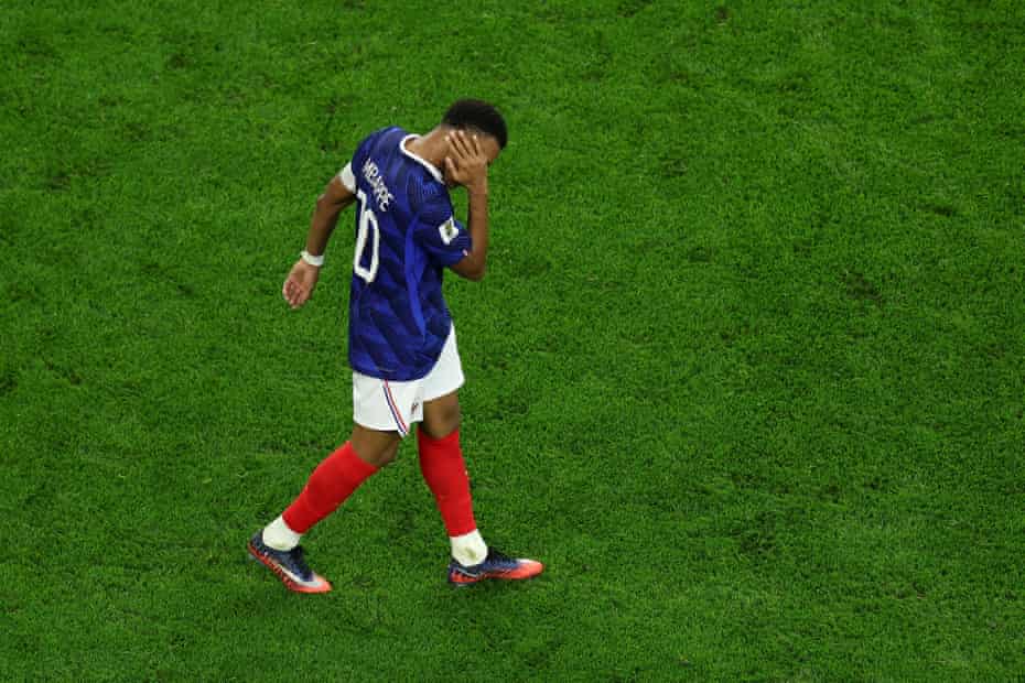Lucas Digne trips Lamine Yamal in the 18-yard box - THEWILL NEWS MEDIA Soccer player in a blue jersey and red socks walks on a grassy field, hand covering face.
