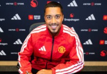 7 Things To Know About Manchester United’s £35m Signing Of Youri Tielemans Man wearing a red Manchester United jacket sits at a desk, signing a document with a pen; a notebook and a smartphone lie on the table in front of him.