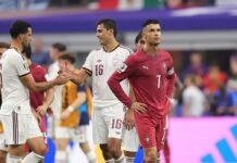 Spain Break Portugal Hearts As Late Winner Ends Ronaldo’s World Cup Dream Portugal player in red jersey #7 stands with hands on hips as teammates in white uniforms shake hands in the background at a stadium.