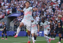 Belgium Outclass USA to Set Up World Cup Quarter-Final Clash with Spain Soccer players in light blue jerseys celebrate a goal on the field as a full stadium of fans cheers in the background.