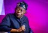 Tinubu Orders EFCC to Unfreeze Osun Account Male performer on stage, wearing a dark pinstripe outfit and a head wrap, holding a microphone under purple lighting