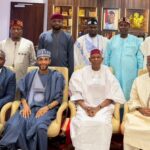 2027: Gov Yusuf Inaugurates Committee To Draft Campaign Blueprint Group of nine men in traditional and formal attire posing for a photo in an office setting, some seated in chairs and others standing behind them.