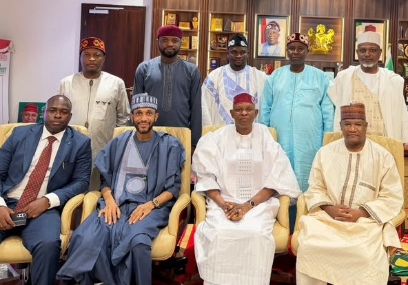 Governor Abba Kabir Yusuf of Kano State has inaugurated a 17-member committee to draft the blueprint for his 2027 governorship campaign. Group of nine men in traditional and formal attire posing for a photo in an office setting, some seated in chairs and others standing behind them.
