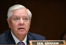 Longtime US Senator Lindsey Graham Dies At 71 Close-up of an older man with white hair speaking at a formal hearing, wearing a dark suit and striped tie.