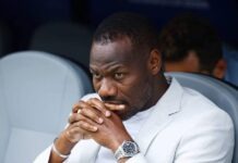 Senegal Sack Pape Thiaw After World Cup Exit Black man in a light blazer seated with hands folded near his lips, looking contemplative.