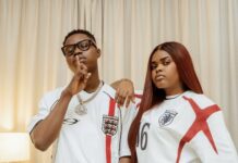 TikTok Stars Jarvis, Peller Set August 1 As Wedding Date Two people in England football jerseys pose indoors: the man with glasses makes a shushing gesture, the woman with long red hair rests her arm on his shoulder.