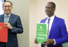 Nigeria Seals Landmark Tax Agreement With Hong Kong to Boost Investment, End Double Taxation Two men in suits hold official folders: one with a red binder, the other with a green booklet, posing for a photo in a formal setting.