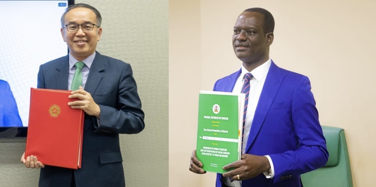 Nigeria’s Minister of Finance and Coordinating Minister of the Economy,. Taiwo Oyedele, and Hong Kong's Secretary for Financial Services and the Treasury, Christopher Hui during the signing of the agreement. - THEWILL NEWS MEDIA Two men in suits hold official folders: one with a red binder, the other with a green booklet, posing for a photo in a formal setting.