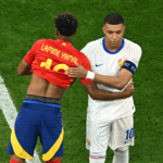 What To Expect In France vs Spain 2026 FIFA World Cup Semifinal Two soccer players hug on a green pitch: one in a red jersey with 'LAMINE YAMAL' and number 10, the other in a white pinstriped kit with blue accents and a captain's armband.