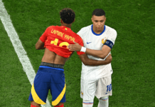 What To Expect In France vs Spain 2026 FIFA World Cup Semifinal Two soccer players hug on a green pitch: one in a red jersey with 'LAMINE YAMAL' and number 10, the other in a white pinstriped kit with blue accents and a captain's armband.