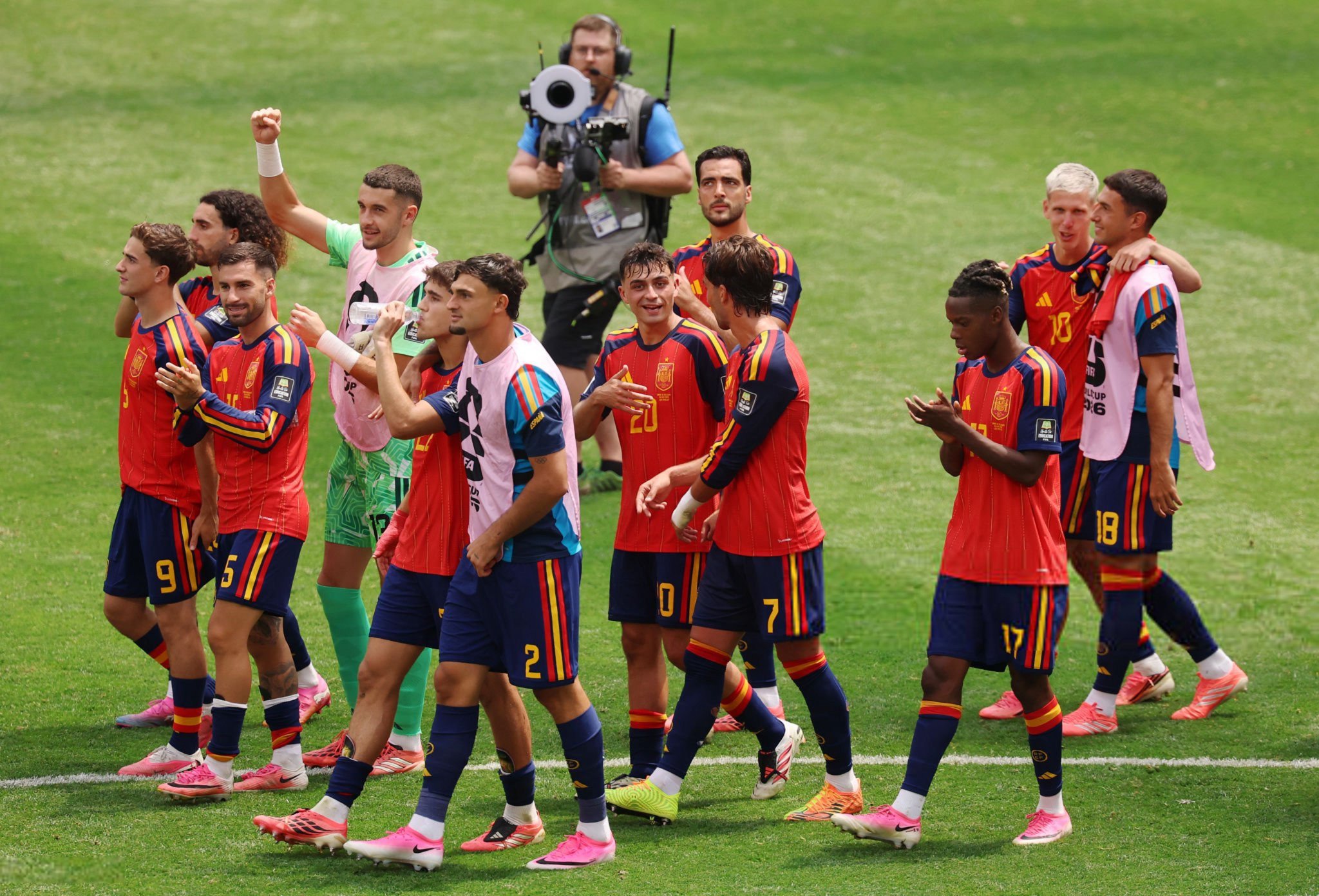 Spain arrive in the semifinals boasting the tournament's best defensive record and an unbeaten run built on discipline and resilience. - THEWILL NEWS MEDIA Group of soccer players in red-and-blue uniforms walking off the field, with a green-clad goalkeeper, while a cameraman films in the background on a grassy pitch.