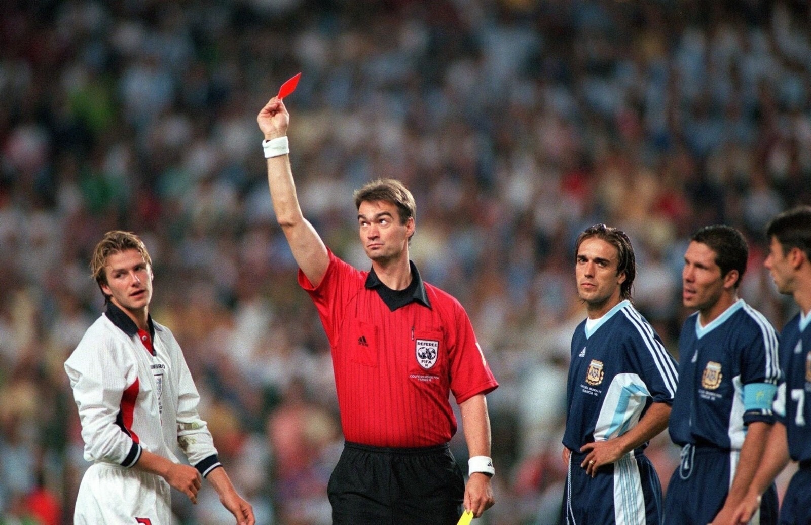 David Beckham Red Card vs Argentina World Cup 1998 - THEWILL NEWS MEDIA Referee in red raises a red card, signaling ejection, while players on the field watch nearby.