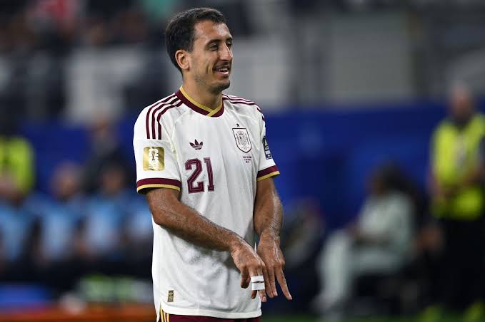 Male soccer player in a white jersey with maroon trim and number 21 on the field during a match.