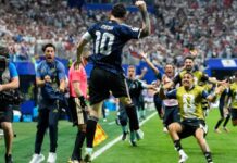 Messi Sparks Late Argentina Comeback to Break England’s Hearts, Set Up World Cup Final Against Spain Messi (number 10) leaps in celebration on a soccer field as photographers and teammates run toward him and a packed stadium cheers behind them.