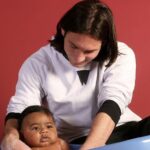 One UNICEF Photo Became Football’s Most Beautiful Prophecy Caregiver washing a baby in a blue tub against a red background, focusing on bath time care