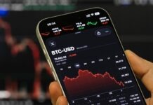 God When? Bitcoin Holders Weep as Index Flashes Single-Digit Premium Close-up of a smartphone screen showing a crypto trading app with BTC-USD and red price charts on a dark background.