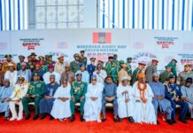 Tinubu Rallies Military, Backs Intelligence-Led Operations to Secure Nigeria Group photo of Nigerian officials and military officers in ceremonial uniforms and traditional dress on a red carpet at the Nigerian Army Day celebration.