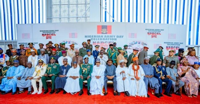 Group photo of Nigerian officials and military officers in ceremonial uniforms and traditional dress on a red carpet at the Nigerian Army Day celebration.