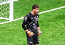 Switzerland Beat Colombia on Penalties to Reach First World Cup Quarter-Final Since 1954 Soccer goalkeeper in black kit with orange gloves standing near a goal, ball at his feet on the green pitch.