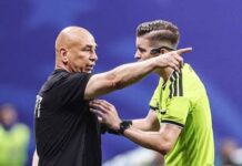 Egypt FA Demands FIFA Investigation Into Referees After Argentina World Cup Defeat Soccer coach in black shirt argues with a neon-yellow referee on the field, pointing emphatically.