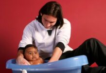 Messi vs Lamine Yamal: 6 Incredible Similarities Ahead of 2026 FIFA World Cup Final Parent bathing a baby in a blue plastic tub on the floor, against a red wall.