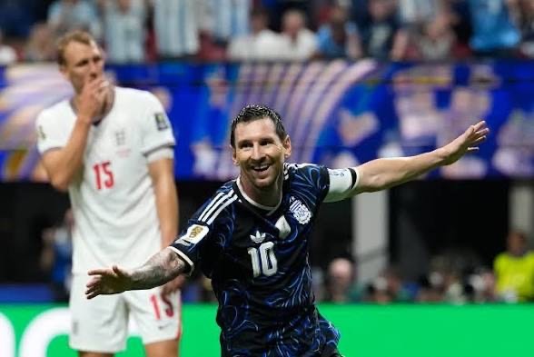 Lionel Messi celebrating Argentina's semifinal victory over England. - THEWILL NEWS MEDIA Lionel Messi (No. 10) celebrates a goal with arms outstretched as England's defender stands in white behind him.