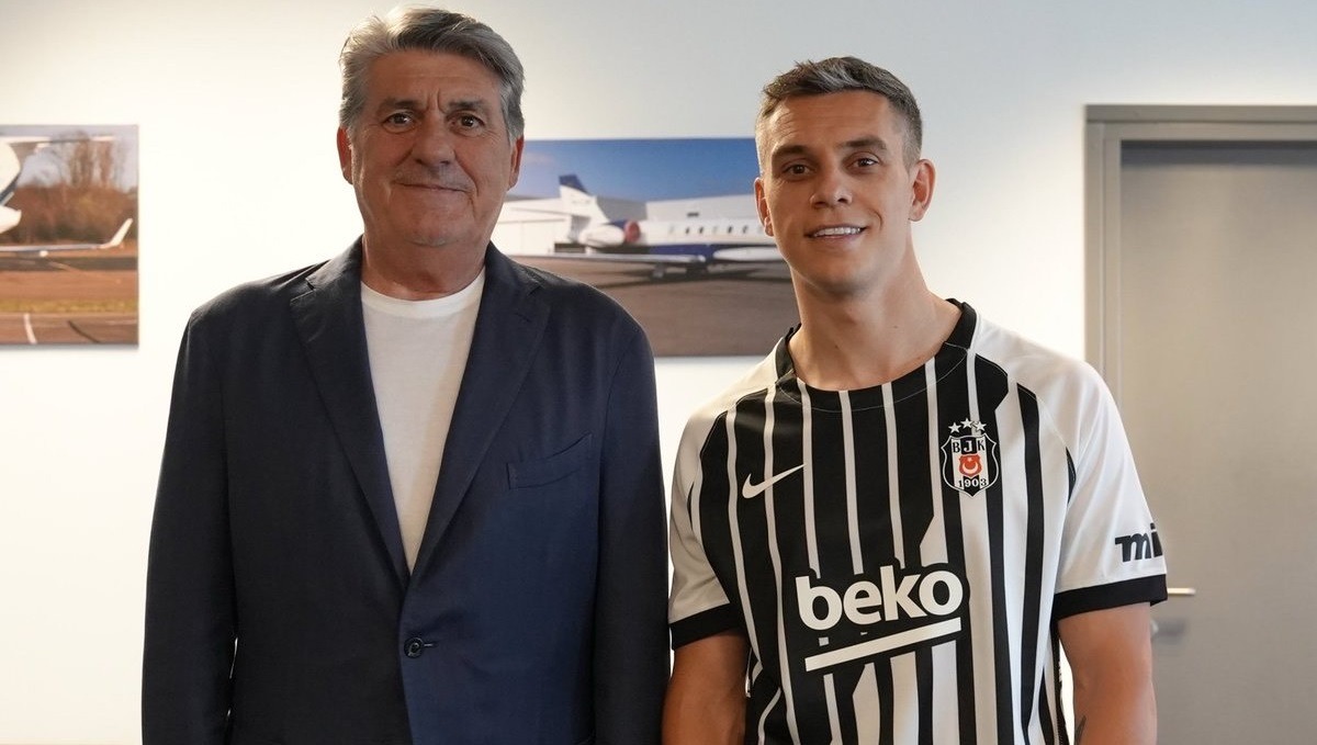 Leandro Trossard - THEWILL NEWS MEDIA Beşiktaş footballer in a black-and-white striped jersey posing with a man in a suit indoors.