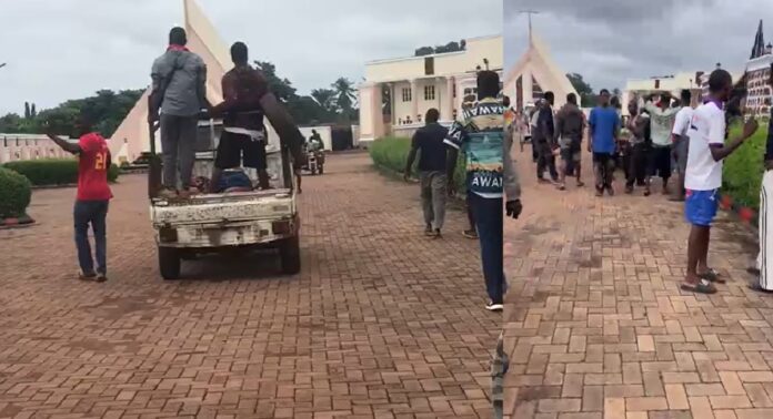Protesters Take Victims’ Bodies To Och'Idoma Palace after Oturkpo Invasion People load a large panel onto a white pickup truck in a brick-paved courtyard as bystanders watch nearby.
