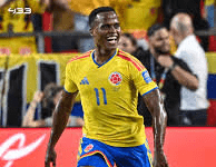 Colombia End Ghana’s World Cup Dream, Advance To Round Of 16 Colombia national team footballer in yellow jersey with number 11 sprinting on the pitch during a match, fans in the stands behind him.