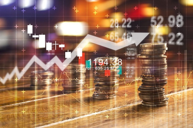 Stacks of coins beside a glowing stock chart and data overlay, illustrating financial growth and investment trends.