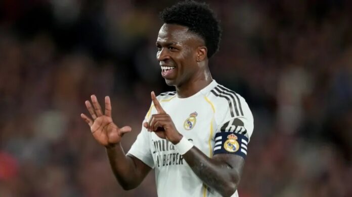 Soccer player in Real Madrid jersey with captain's armband celebrating, smiling and gesturing with hands.